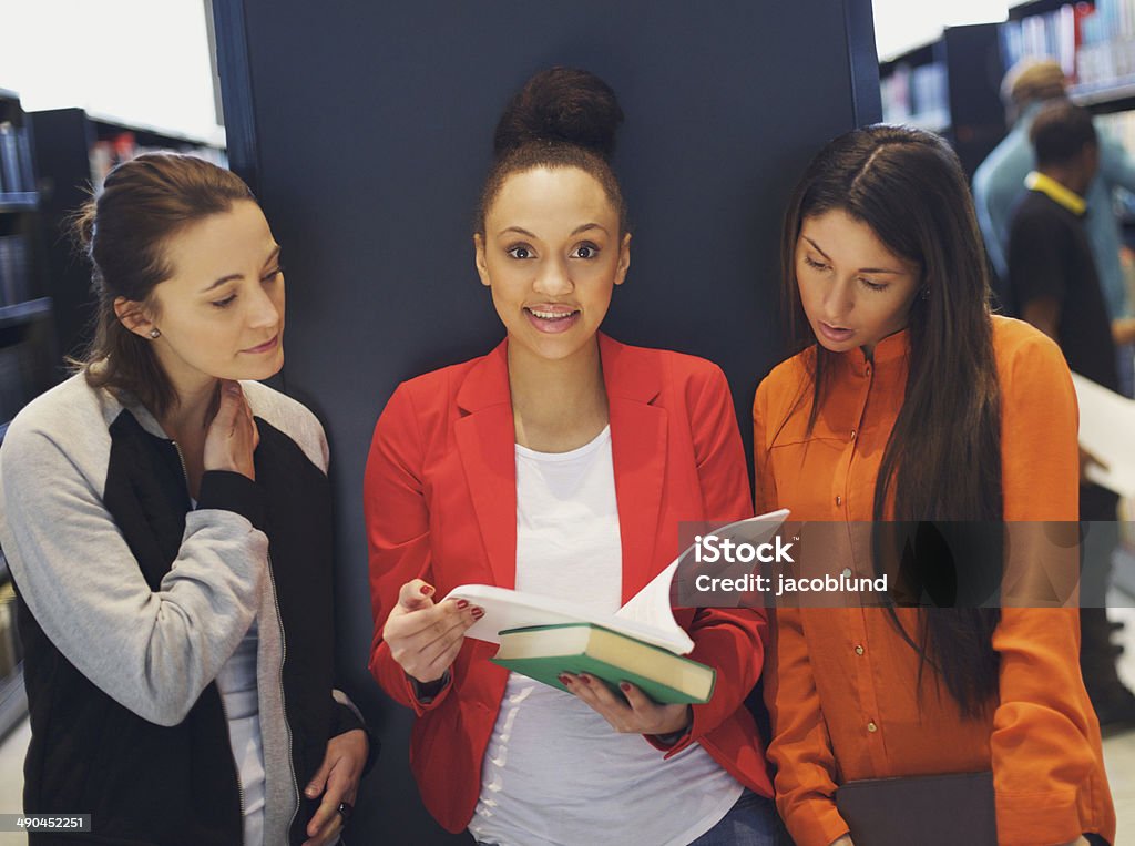 Young female students studying together for exams Three young female students standing in public library with books. Young women sharing books for theirs studies. 20-29 Years Stock Photo