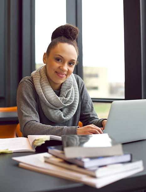 молодая женщина, изучая на столе, используя ноутбук с книгами и - изучая стоковые фото и изображения