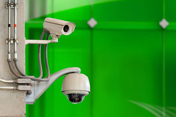 istock CCTV camera or surveillance operating on green wall background 490457701