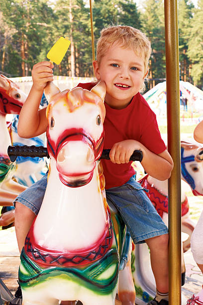 istock curly little boy riding a carousel 490458307