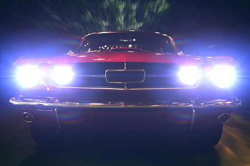 Close-up of retro car with bright headlights on.