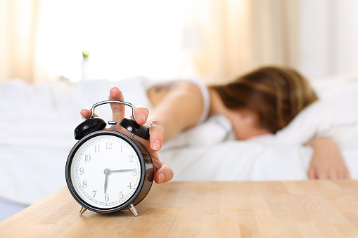 Sleepy joven mujer tratando de forma reloj despertador photo
