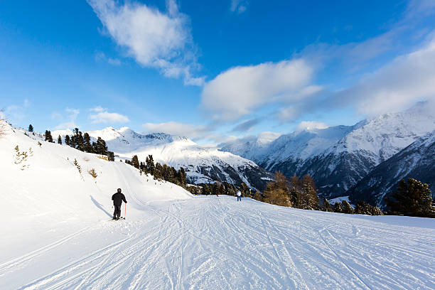 Male skier skiing on easy ski piste on a sunny winter day.
