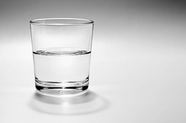 Half full, half empty glass of water Half full, half empty glass of water on a white background with  gray shadow half full stock pictures, royalty-free photos & images