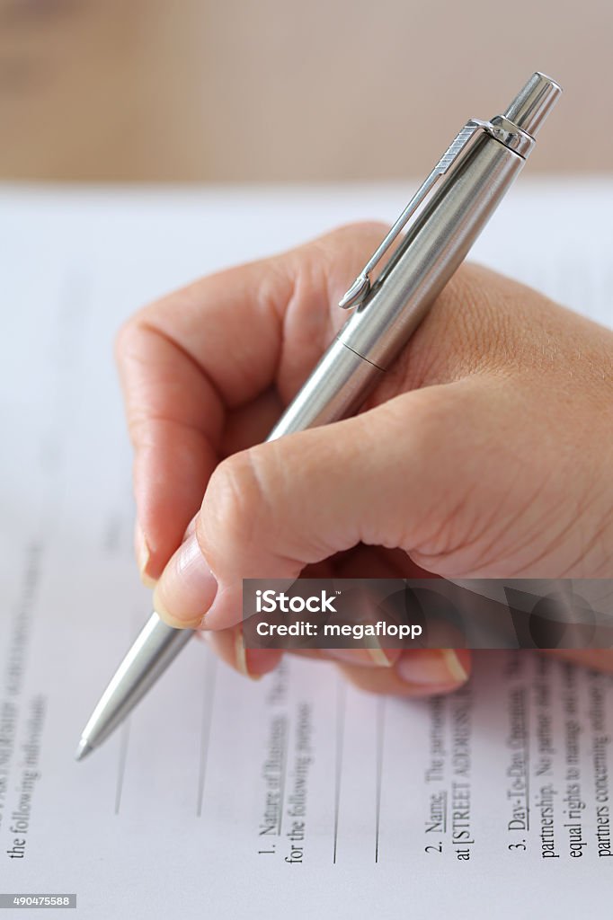 Signing document Hand of businesswoman filling and signing with silver pen partnership agreement form clipped to pad closeup. Business success, contract, paperwork or lawyer concept 2015 Stock Photo