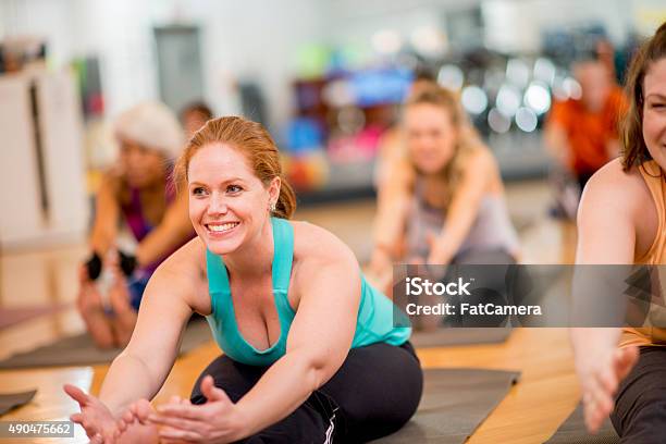 Forward Fold In Yoga Fitness Class Stock Photo - Download Image Now - Yoga Class, Indoors, Multiracial Group