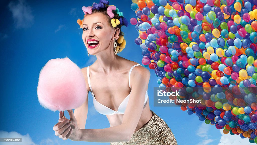 Smiling happy girl posing. Beautiful crazy girl holding sweet candy cotton. Sky and balloons on background. 2015 Stock Photo