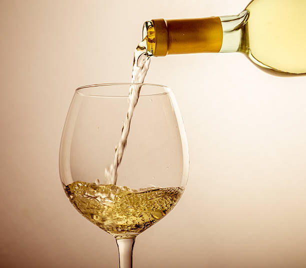 istock White wine pouring in glass from a bottle 490483180