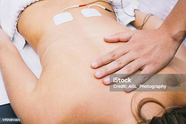 Hand And Electrodes On A Patients Lumbar Stock Photo - Download Image Now - Electrode, 2015, Adult