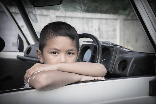 Young Asian boy trapped in a car, looking lost and alone.