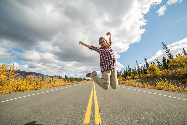 Cheering woman jumping high up on road