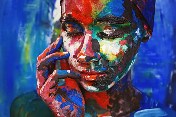 Photo of Living painting - young woman completely covered with thick paint