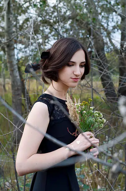 Photo of Young tender woman with black hair, field flowers