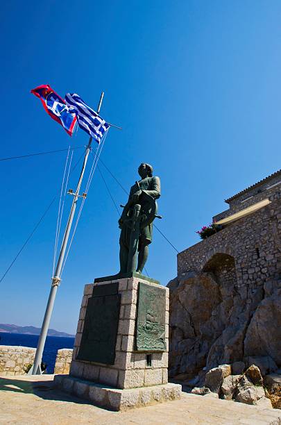 Hydra, Greece: 18 August 2012 - The statue of Andreas Miaoulis, a hero of the Greek war of independence, which is a landmark of the Greek island, Hydra. On the background the flag of Hydra and Greece.