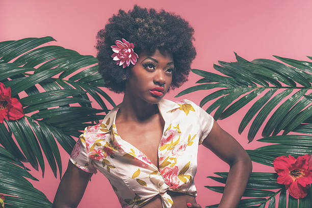 sensual afro americano de pin-up entre las hojas. contra fondo rosa. - pinup model fotografías e imágenes de stock
