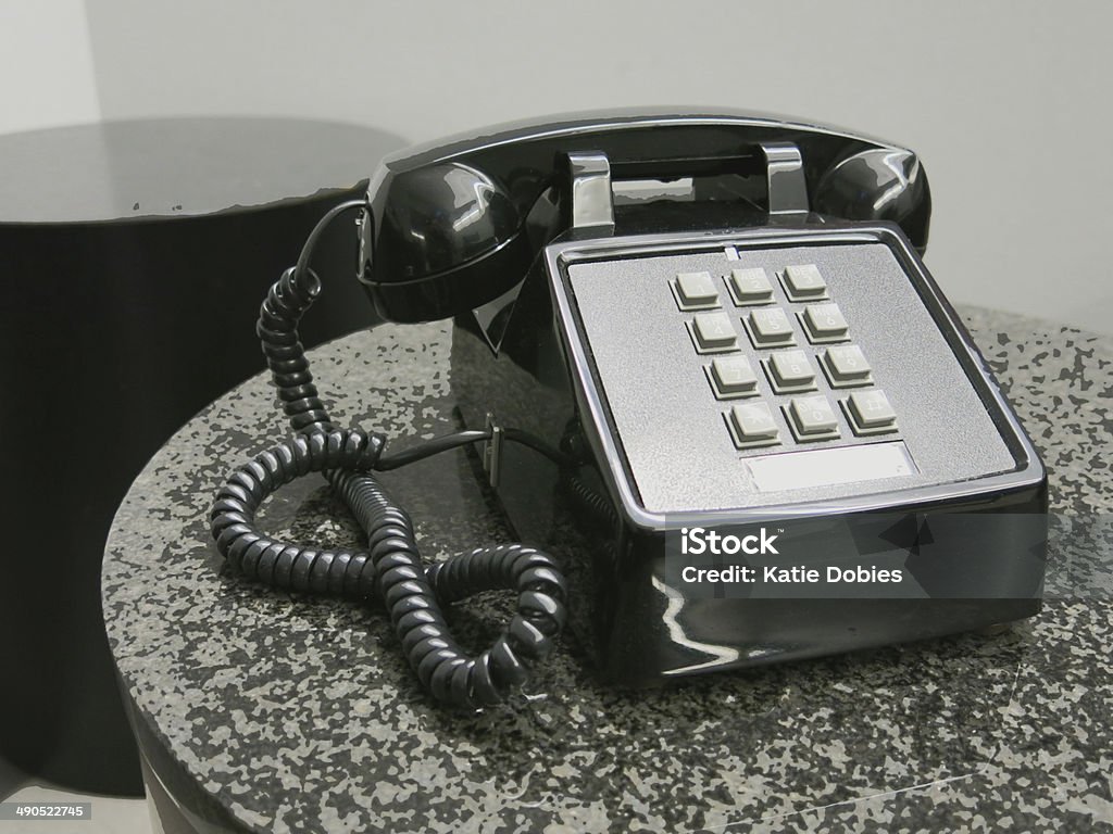 Black Push Button Waiting Room Phone in Gray Room Black push button phone with cord on table in waiting room at an office. 1970-1979 Stock Photo