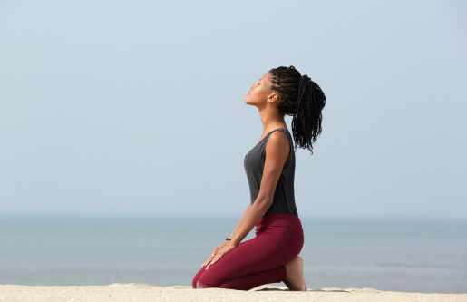 Portrait of a beautiful young african american woman meditating at the beach enjoying summer