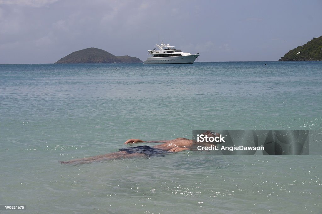 Good Life Man floating at the beach with yacht in background. Caribbean Sea Stock Photo