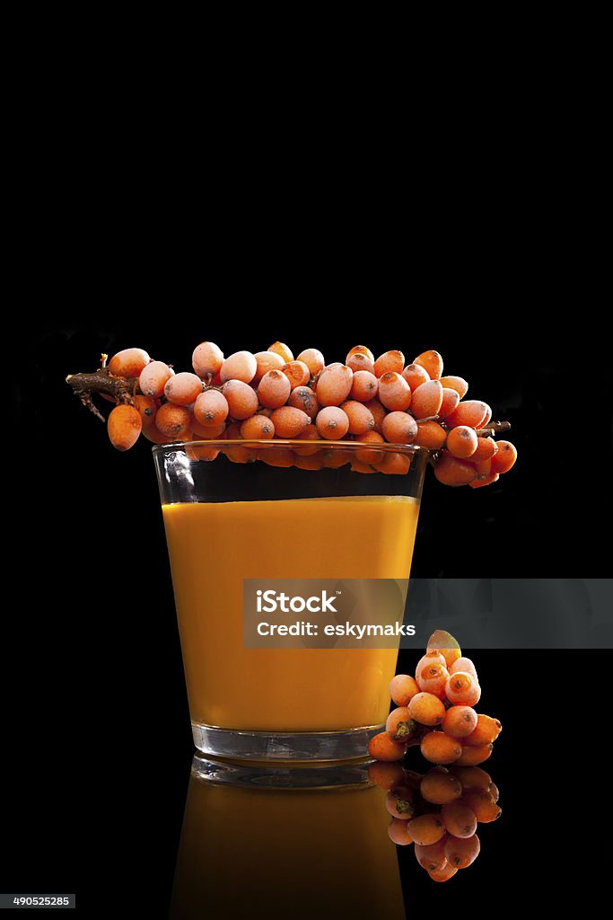 Sea buckthorn juice on black. Sea buckthorn juice and frozen berries isolated on black background. Alternative medicine. Detox. Alternative Medicine Stock Photo