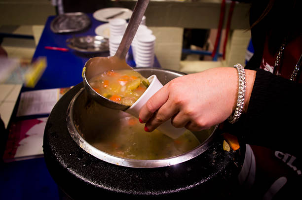 Cawl or soup being poured into a cup Cawl (Welsh soup/broth) being poured into a cup.  Soup-kitchen style image, with some movement. soup kitchen stock pictures, royalty-free photos & images