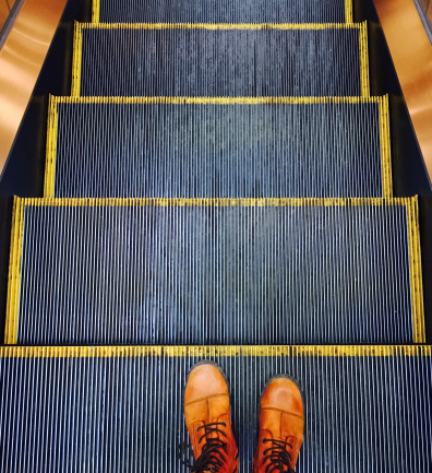 Person in orange boots going down on the escalator.