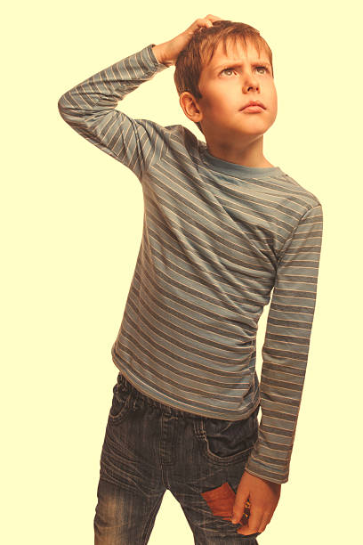 istock blond kid boy in a striped sweater thinks scratching his 490527115