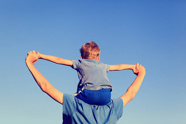 istock happy father and son on shoulders play at sky 490543832