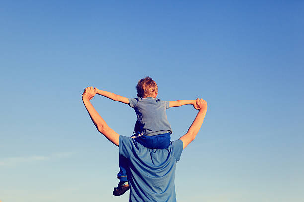 istock happy father and son on shoulders play at sky 490543886