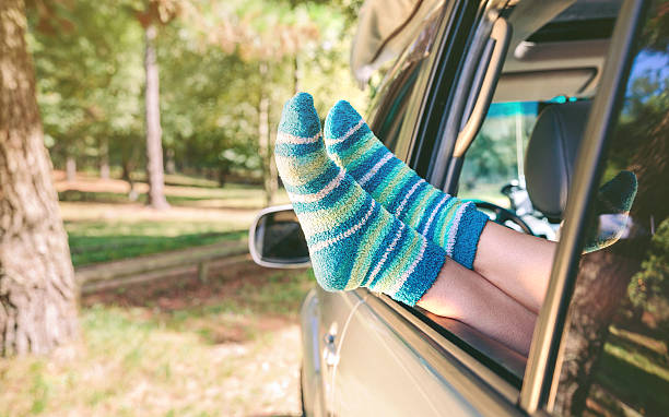 istock Female legs with socks resting over open window car 490546412