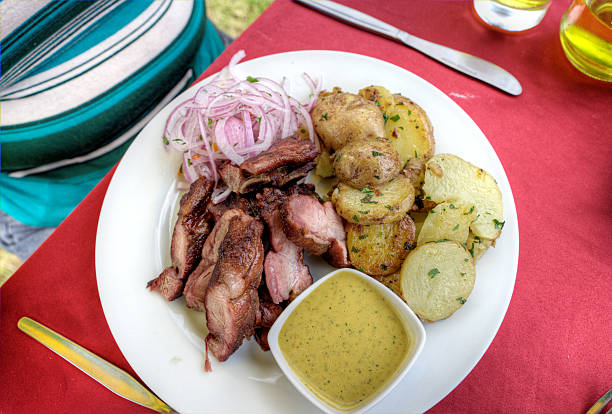 Traditional Peruvian meal of chicharones - fried pork with potatoes, onion and bowl of dipping sauce