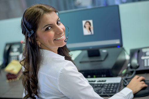 Customer support operators working at a call centre wearing a headset and looking at the camera smiling