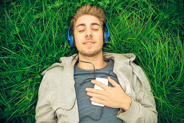 istock Young man with headphones lying down in the grass 490551148