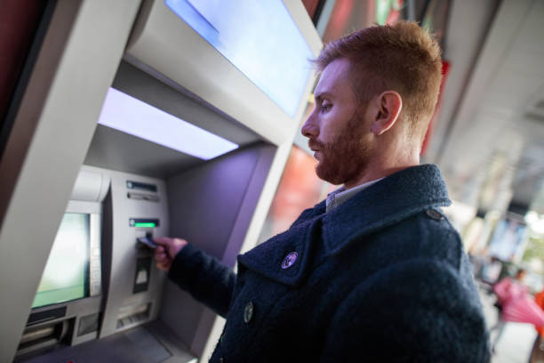 istock Young redhead businessman withdrawing money from ATM machine. 490551700