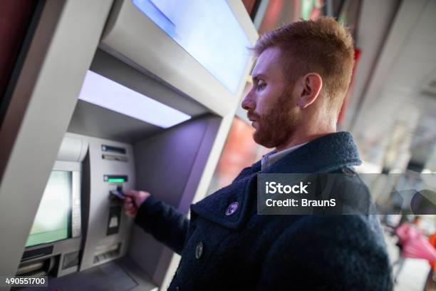 Young Redhead Businessman Withdrawing Money From Atm Machine Stock Photo - Download Image Now