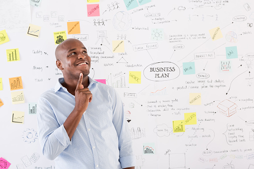 Creative man thinking about a business plan with a wall chart at the background