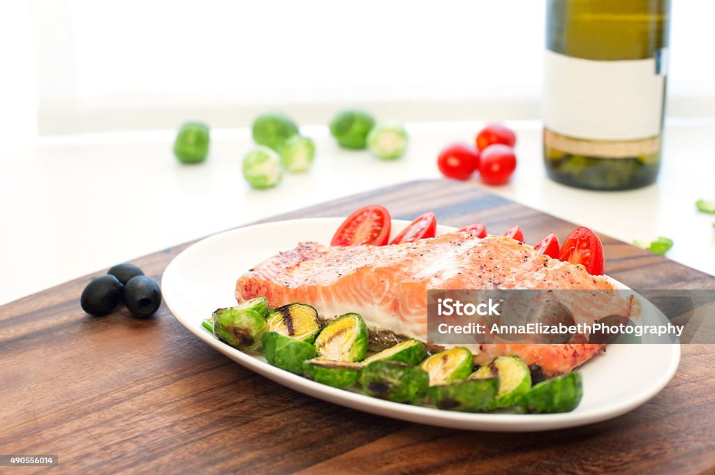 Piece of roasted salmon fillet with grilled vegetables Piece of roasted salmon fillet with grilled brussels cabbage and tomatoes. Indoors still-life. 2015 Stock Photo