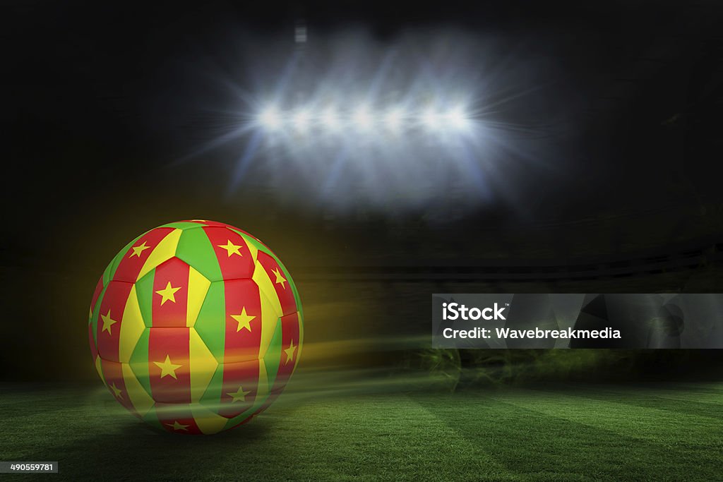 Football in cameroon colours Football in cameroon colours against football pitch under spotlights Cameroon Stock Photo