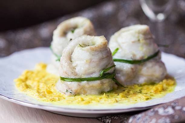 Rolls of white fish fillet, lentil creamy sauce stock photo