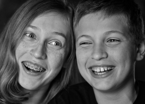 A brother and sister share a laugh in b&w.