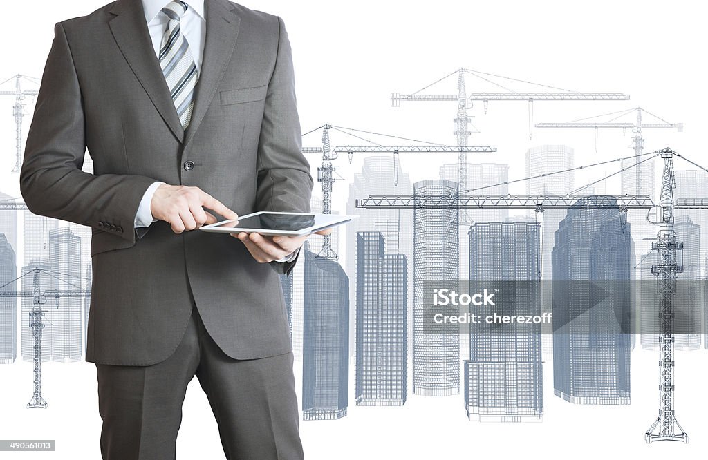 Businessman in suit hold tablet pc Businessman in suit hold tablet pc. Wire frame tower crane and skyscrapers on the background Construction Industry Stock Photo