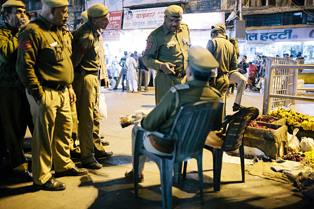 Delhi, India - March 8, 2014: A small group of police meet and discuss on a street in Delhi, New Delhi, India. The superior officer is seated whilst his colleges stand.