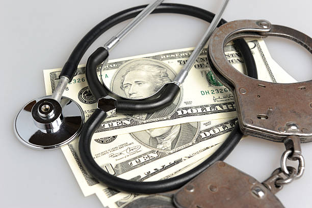 Stethoscope, handcuffs and money on gray Stethoscope, handcuffs and money on gray background restraining device stock pictures, royalty-free photos & images