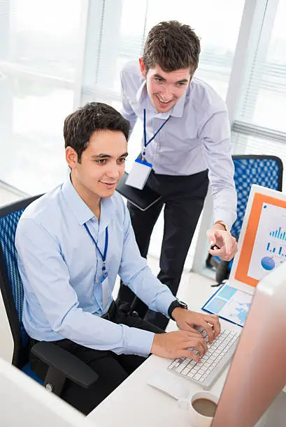 Office worker showing something to his colleague on monitor