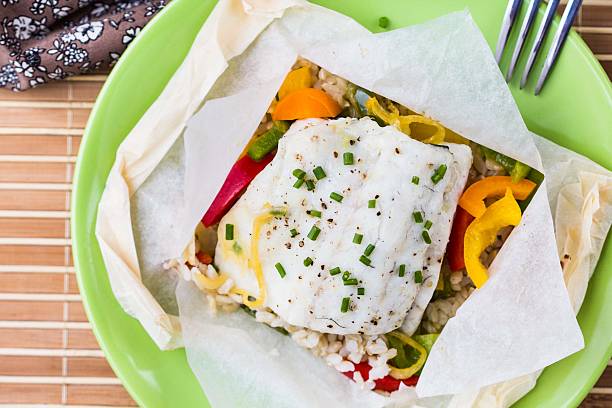 White fish fillet baked in paper, parchment with rice, pepper stock photo