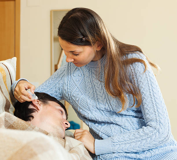 istock Young woman dripping ear drops to man 490579915