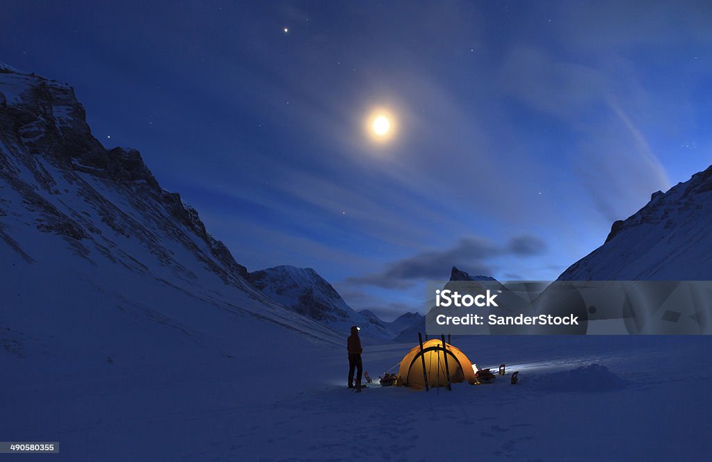 Mountain campsite Woman looking at the night sky while camping in the snow covered mountains in Swedish Lapland (Nallo). Camping Stock Photo