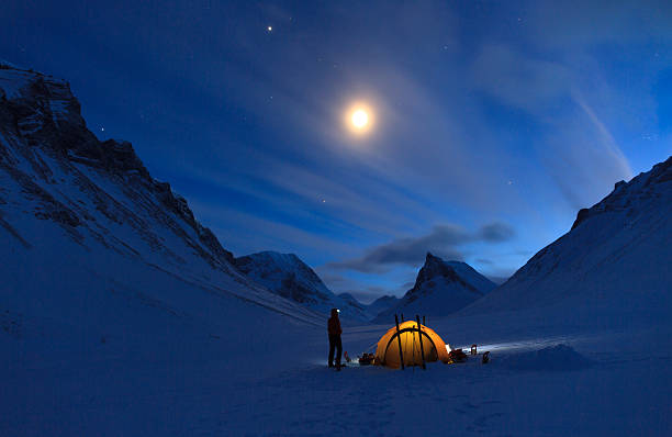 Mountain campsite Woman looking at the night sky while camping in the snow covered mountains in Swedish Lapland (Nallo). polar climate stock pictures, royalty-free photos & images