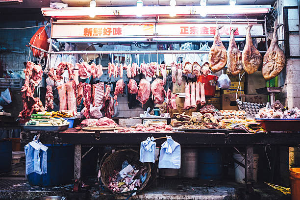 An outdoor meat market in downtown Hong Kong, assorted cuts from a variety of animals hang on display, waiting to be sold.