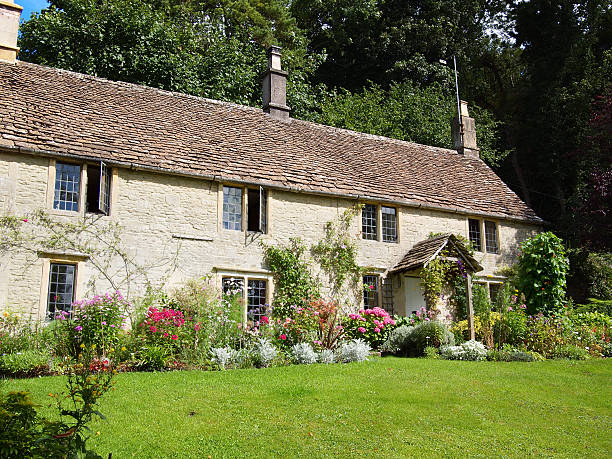 English village thatched cottage garden framed by a hedge and gate