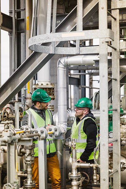 istock Coworkers talking while standing by machines at factory 490591624